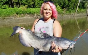 Ann is also an accomplished angler as demonstrated by this photo with a nice channel cat. She is sporting one of her Pink Catfish designs made especially for women. 