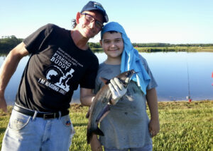 A father and son are all smiles after landing a healthy channel catfish on one of the Fish Orlando program’s Urban Ponds.