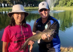 Fishing mentors from the local community pitch in to help young anglers bait lines and land channel catfish during a Fish Orlando kid’s fishing event.