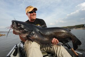 Cory Schmidt of Merrifield, Minnesota is all smiles after catching this 50-pound-plus blue cat in Arkansas’ Lake Ouachita. Cats almost twice this size have shown up in this 40,000-acre lake in recent years. | Lakes for Winter Catfishing