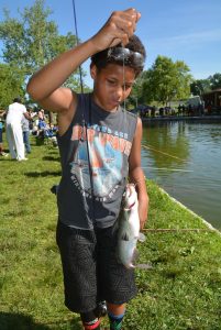 A young angler examines his catch during a kids’ fishing derby at an urban lake in Kansas City.