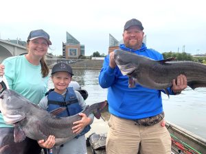 Capt. Sam Simons’ clients—Bayleigh, Nathan and Jake—show off an impressive double on blues they caught in downtown Chattanooga, again with the familiar Tennessee Aquarium in the background.