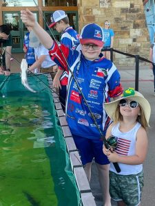 Caption: Austin and Kaitlyn Dollar at a Cabela’s Catfish Pond where they now help other children with clinics. (Photo by Holly Dollar)