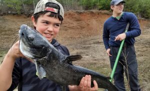 Cold day, warm smile. Winter catfishing on a pond bank can surprise kids with fish like this.